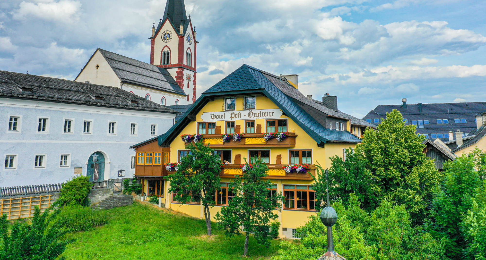 Exterior shot of the Hotel Post Örglwirt with the Mariapfarr pilgrimage basilica in the background