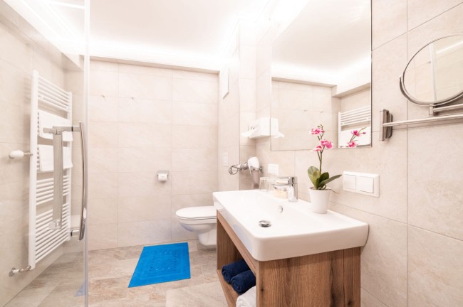 Badezimmer mit Waschbecken, Dusche und Handtuchtrockner