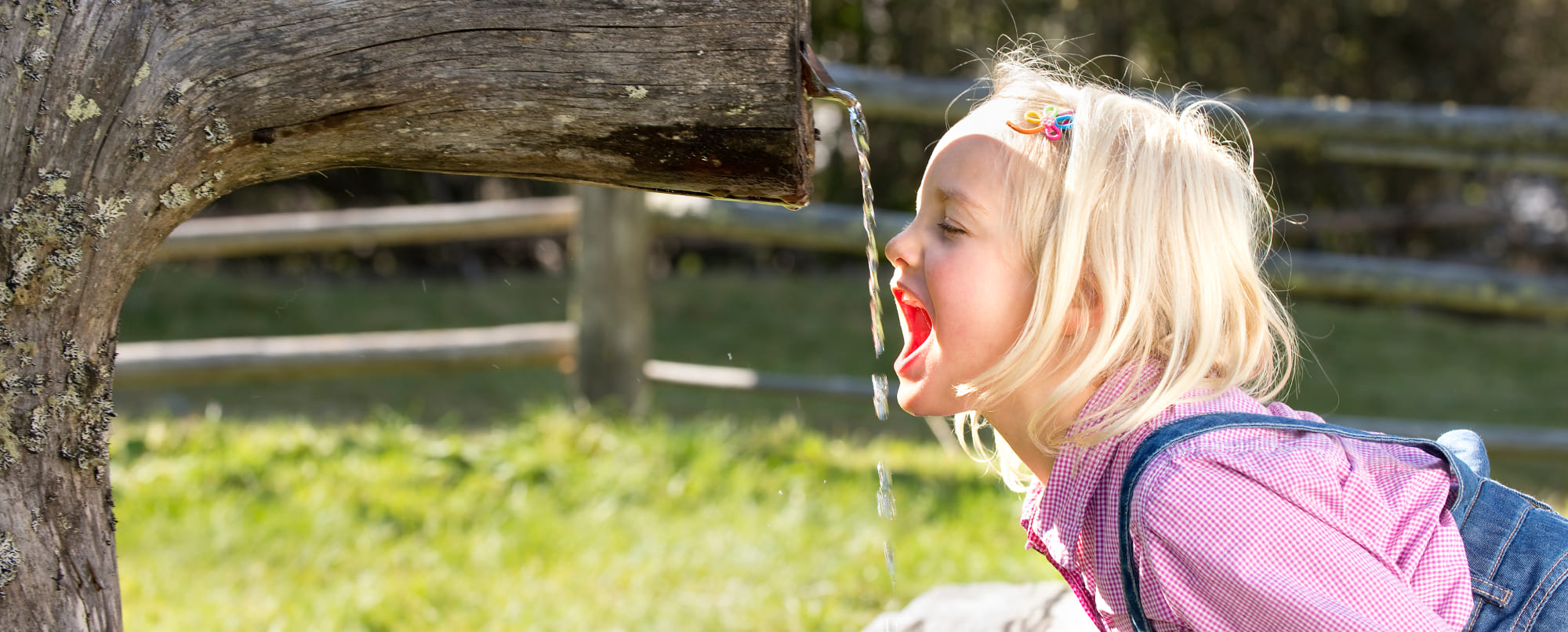 Kind trinkt aus Brunnen im Urlaub im Salzburger Lungau